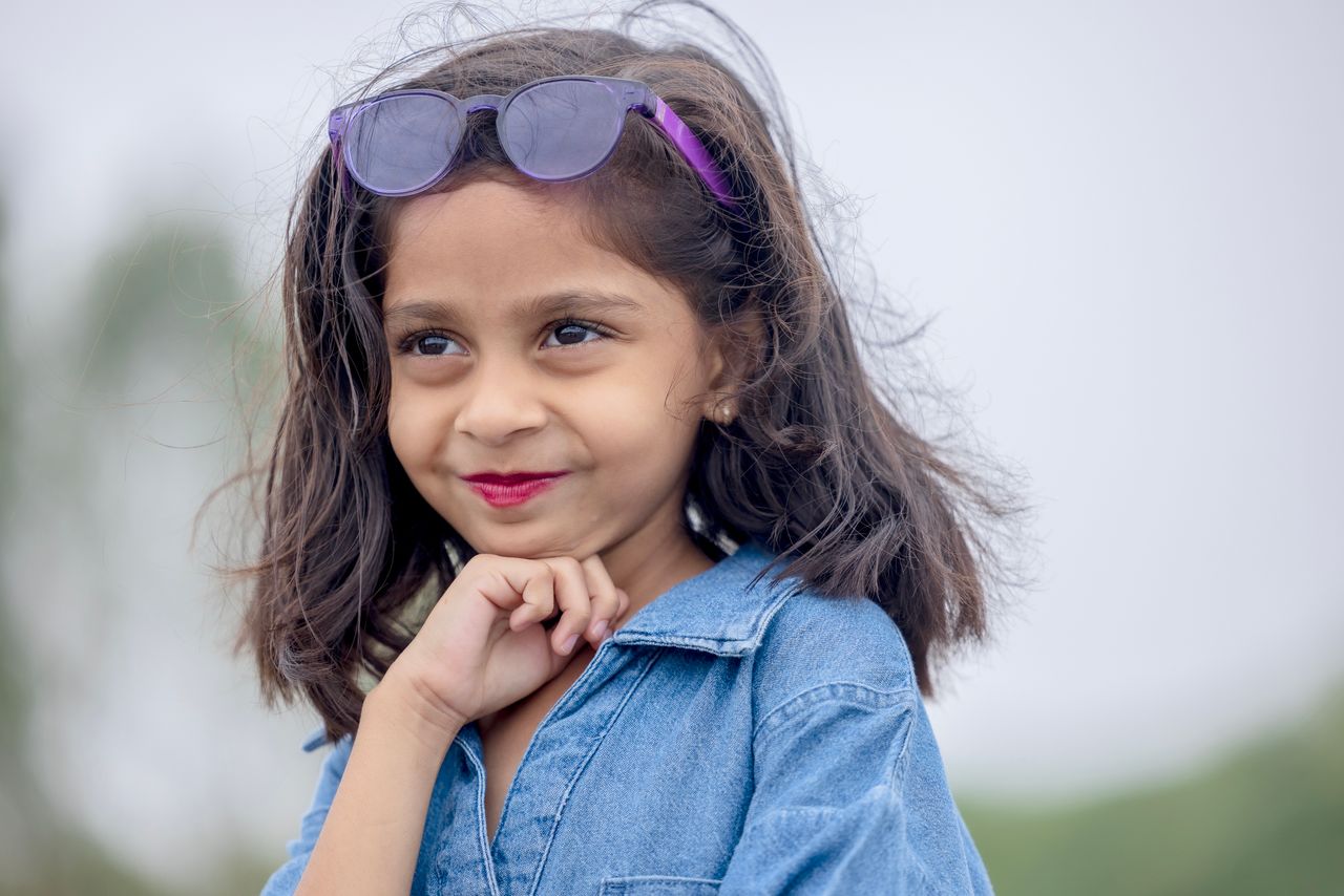 Crafting Captivating Headlines: Your awesome post title goes here Portrait of a smiling young girl wearing sunglasses and denim outdoors, exuding joy and playfulness.
