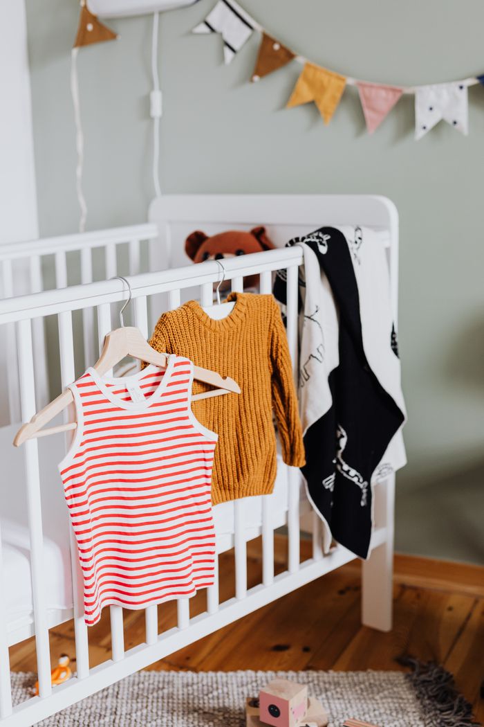 The Art of Drawing Readers In: Your attractive post title goes here A warm baby room with a crib, clothes, and playful decorations.
