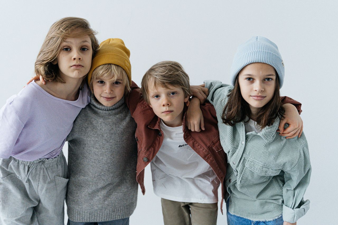 Services Children posing together in trendy casual outfits with hats indoors.